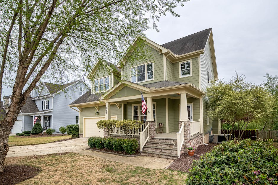 Well-landscaped house with mature trees and American flag on front porch