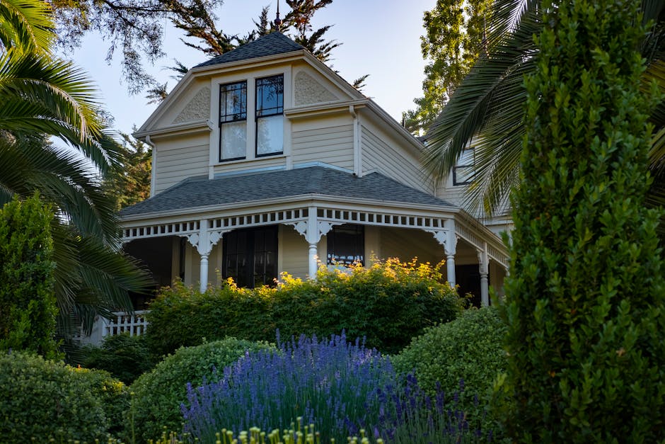 Small trees and flowering shrubs in front of a Victorian-style house